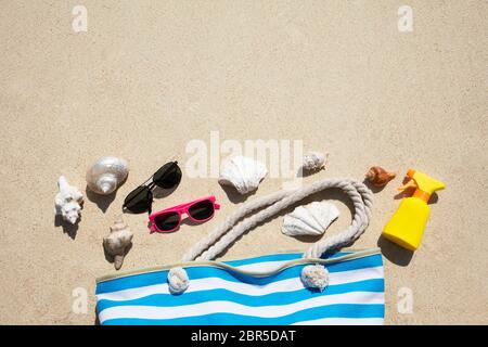 Les coquillages, lunettes de soleil, crème solaire et Bouteille Sac à Sand At Beach Banque D'Images