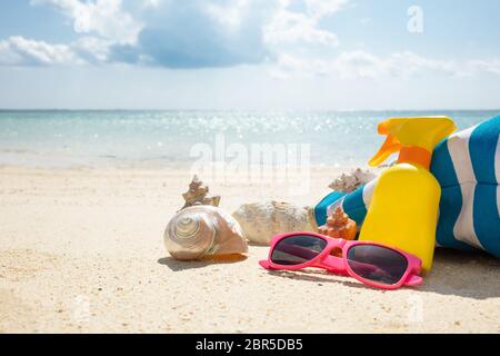 Lunettes de soleil, crème solaire, de coquillage et de sacs à main On Beach Banque D'Images