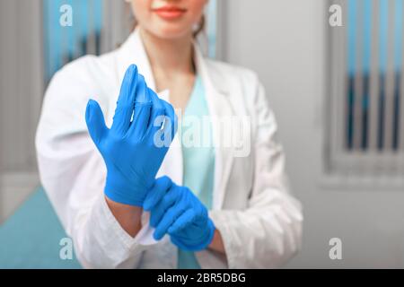 Mains du médecin mettant des gants en latex dans un hôpital. Femme dans un maque de médecin en gants de latex. Protection contre les virus et les bactéries. Kovid 19 Banque D'Images