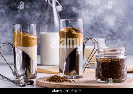 Café Dalgona Latte Espresso avec une mousse fouettée fraîche et moelleuse dans des verres sur fond gris. Banque D'Images