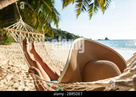 Close-up of a Woman in Bikini Wearing Hat Lying On Hammock At Beach Banque D'Images