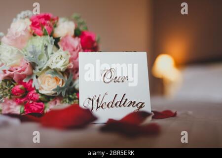 Boîte avec l'inscription notre mariage se trouve sur le lit avec un bouquet de brides Banque D'Images