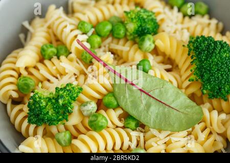 Pâtes aux légumes verts et au parmesan. Salade de pâtes de fusilli végétaliens au brocoli et aux pois verts Banque D'Images