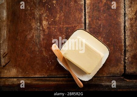 Pat de jaune beurre frais de la ferme sur une plaque avec un diffuseur en bois sur une vieille table en bois avec copie espace Vue de dessus Banque D'Images
