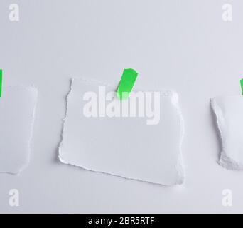 Arrachée morceau de papier blanc collé à velcro vert, fond blanc Banque D'Images