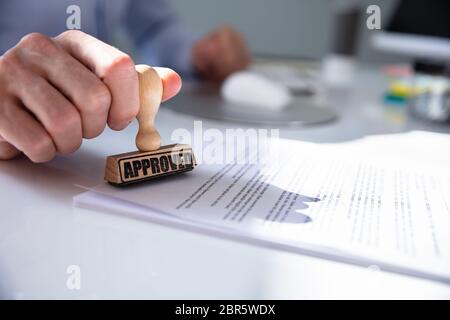 Close-up of a person's Hand Stamping avec timbre approuvé sur le document At Desk Banque D'Images