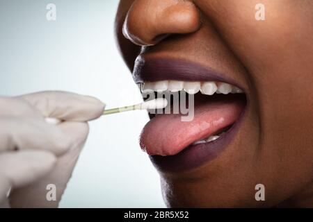 En tenant la main du dentiste de test de salive bouche de femme avec du coton-tige Banque D'Images