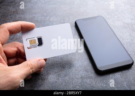 De l'homme près de la carte SIM du smartphone sur le fond en béton Banque D'Images