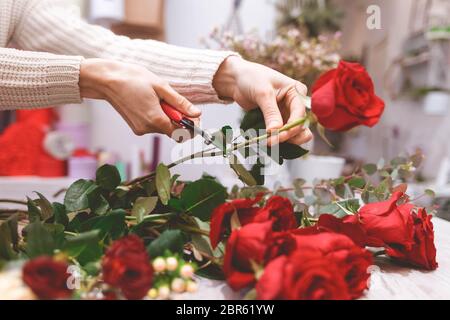 Le vendeur de fleuriste prépare des roses pour créer un bouquet en les élaisant Banque D'Images