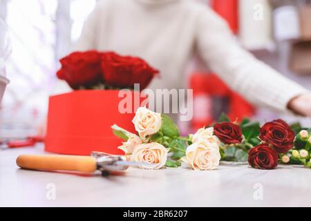 Fleuriste fleuriste femme faisant boîte avec roses rouges. Processus de création de chapeau-boîte avec des fleurs Banque D'Images
