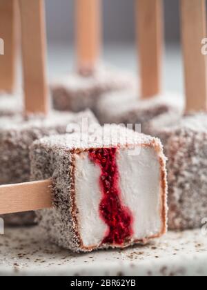 La crème glacée faite maison lamington raw pop sur fond clair. Australian dessert sucré avec lamington chia et framboises Confiture, Chocolat et cacao manteau. Banque D'Images