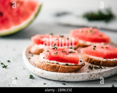 Toasts avec du fromage à pâte molle, de la pastèque et thym frais.salé sucré,fromage pastèque et épicé sur croquant de thym pain grillé tranches. Idée et recette pour Banque D'Images