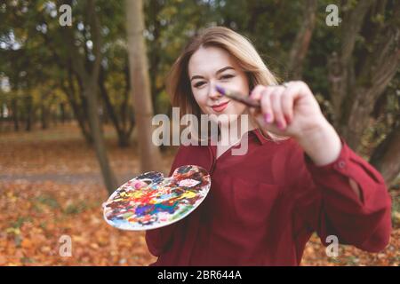 Jeune fille peintre tient une brosse et une palette dans ses mains Banque D'Images