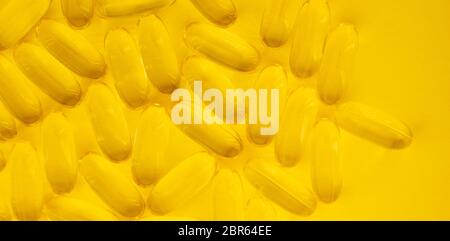 Bannière faite de capsules de produit de supplément d'huile de poisson Omega 3 isolées sur fond jaune de près. Banque D'Images