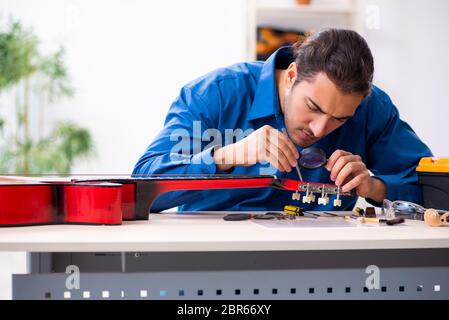 Jeune homme réparateur de la guitare Banque D'Images