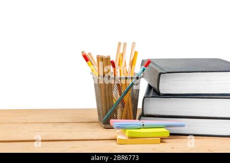 Pile de livres avec notes stylo et papier avec des crayons dans panier conteneur sur table en bois isolé sur fond blanc. Concept Retour à l'école Banque D'Images