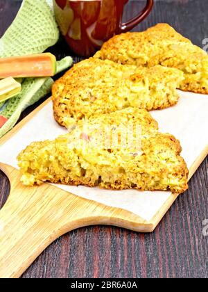 Des scones à la rhubarbe sur parchemin, serviette et d'un bords de la rhubarbe sur le fond de planche de bois Banque D'Images