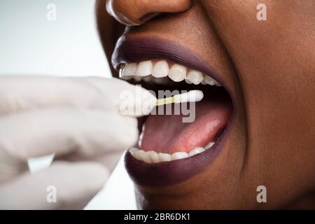 En tenant la main du dentiste de test de salive bouche de femme avec du coton-tige Banque D'Images