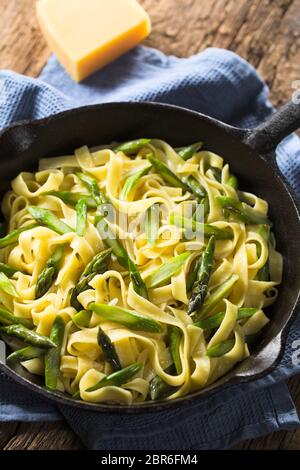 Des pâtes fraîches plat de fettucine ou tagliatelle, asperges vertes, l'ail et le jus de citron dans la poêle en fonte (Selective Focus, Focus un tiers Banque D'Images