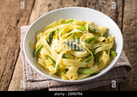 Des pâtes fraîches plat de fettucine ou tagliatelle, asperges vertes, l'ail et le jus de citron dans un bol (Selective Focus, Focus sur la tête d'asperge Banque D'Images