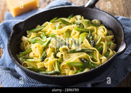 Des pâtes fraîches plat de fettucine ou tagliatelle, asperges vertes, l'ail et le jus de citron dans la poêle en fonte (Selective Focus, Focus un tiers Banque D'Images