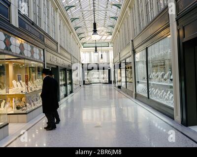 Deux agents de sécurité bien habillés patrouillent une Argyll Arcade déserte, qui se spécialise dans les magasins de bijoutiers de grande valeur dans le centre de Glasgow pendant la pandémie de coronavirus et le confinement. Banque D'Images