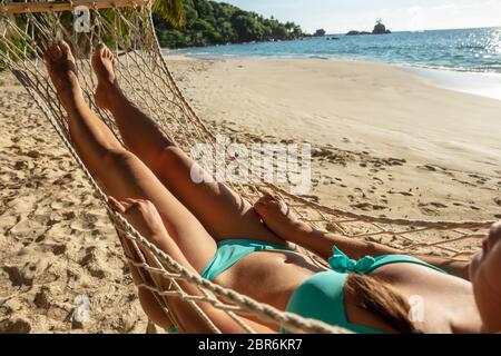 Close-up of a Woman in Bikini Wearing Hat Lying On Hammock At Beach Banque D'Images