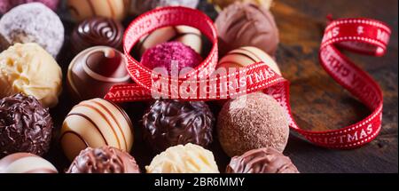 Fête du ruban rouge Joyeux Noël fit tourner sur une sélection de chocolats artisanaux gastronomique différent dans panorama format bannière Banque D'Images