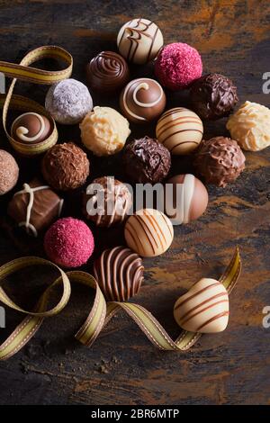 Chocolat praliné ou luxe Valentines assortiment avec des bonbons à la main et d'un seul coeur avec ruban fit tournoyer en chocolat vue high Banque D'Images