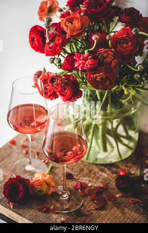 Vin rose en verres et bouquet de fleurs de printemps rouges sur fond rustique de table en bois. Boutique de vins, bar, dégustation de vins, concept de carte des vins Banque D'Images