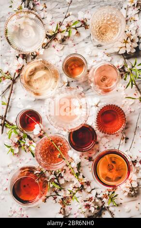 Différentes nuances de vin rose. Plat de vin rose de différentes couleurs en verres et fleurs printanières sur fond blanc, vue du dessus. Vin sho Banque D'Images