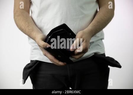 Jeune homme en Jean avec des poches vides montre son portefeuille vide Banque D'Images