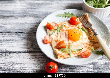 Crêpes avec des œufs, du fromage, de roquette et de tomates.Galette complète. Plat traditionnel galette sarrasin Banque D'Images