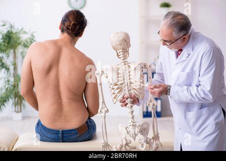 Jeune homme blessé au dos, rendant visite à un médecin expérimenté Banque D'Images