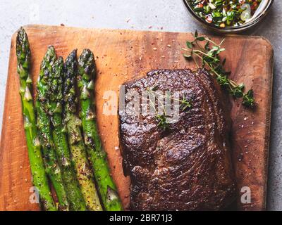 steak de bœuf, mouton rôti aux asperges sur un plan de coupe, sauce à l'huile d'olive et aux herbes, épices, gros plan Banque D'Images