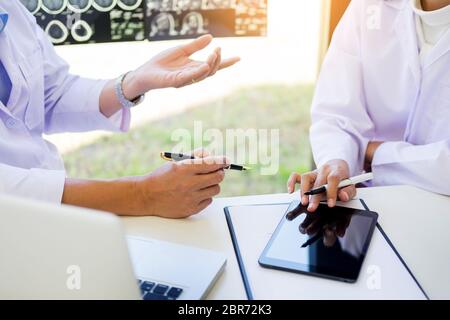 Deux médecins l'analyse d'une numérisation ou x-ray film ou explique un scanner avec des expressions réfléchies avec la méthode de traitement du patient les résultats o Banque D'Images