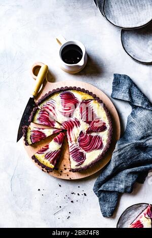 Tarte à la crème de poire pochée au vin rouge sur une table de service en bois. Banque D'Images