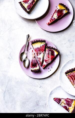 Tarte à la crème anglaise avec des poires pochées au vin chaud sur les assiettes. Banque D'Images