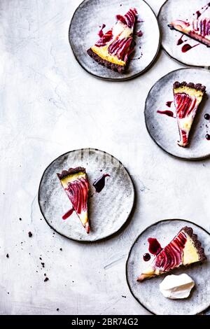 Tarte à la crème de poire pochée au vin rouge sur les assiettes de service. Banque D'Images