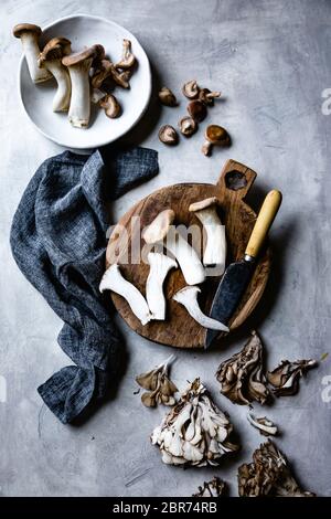 Trompette et champignons maitake sur une planche à découper en bois. Banque D'Images