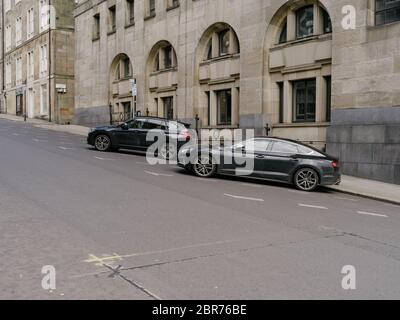 Deux voitures de prestige noires garées dans une rue vide du centre-ville de Glasgow, habituellement très fréquenté, pendant la pandémie du coronavirus britannique et son confinement. Banque D'Images