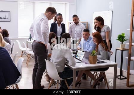 Groupe de jeunes gens d'affaires diversifié et de communiquer tout en restant assis au bureau 24 Banque D'Images