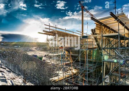 Photo en gros plan du nouveau site de construction de pont avec construction à temps pour le remplir de béton. Tour de grue jaune, contre le soleil, ciel profond Banque D'Images