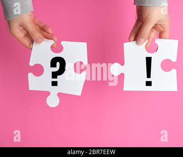 Grand puzzle en blanc sur fond rose main de femme, concept d'entreprise, vue d'en haut Banque D'Images
