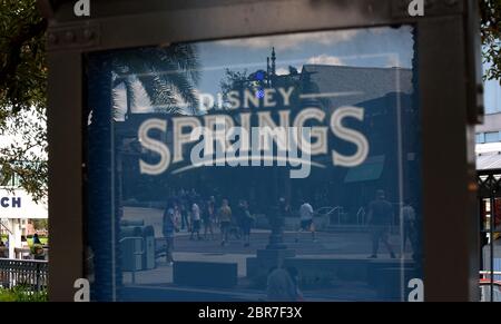 Les visiteurs de Disney Springs à Walt Disney World sont vus dans une réflexion sur le jour où le complexe de vente au détail, de restauration et de divertissement commence une réouverture progressive après la fermeture du parc thématique le 16 mars 2020 en raison de la pandémie de coronavirus. Tous les visiteurs de Disney Springs devront porter des revêtements de visage et les soumettre aux contrôles de température. Banque D'Images