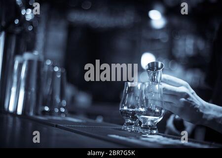 Gros plan d'un bartender pouring dans un verre de whisky Glencairn. Banque D'Images
