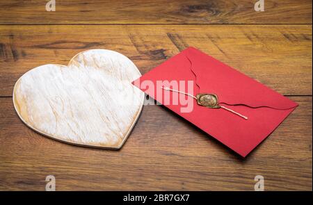 Décoration classique rétro de la Saint-Valentin, grande enveloppe en bois peinte blanc hart, isolée, rouge avec joint en cire, sur des panneaux en chêne d'époque, vue avant Banque D'Images