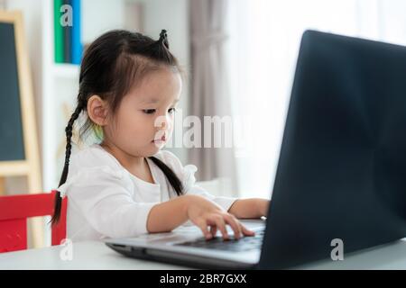 École maternelle asiatique de fille vidéo conférence e-learning avec enseignant sur ordinateur portable dans le salon à la maison. Homeschooling et l'apprentissage à distance, en ligne Banque D'Images