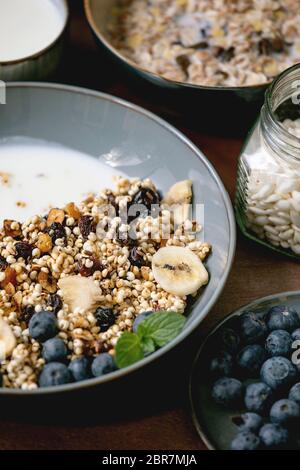 Granola de grain de millet croustillant maison avec fruits secs et noix dans un bol en céramique, avec yaourt, menthe et ingrédients ci-dessus. Texture marron sous-groupe Banque D'Images