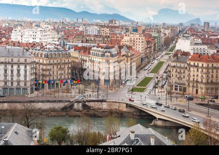 Scenic Vue aérienne de les rives de la rivière Isère, pont, les toits et les Alpes françaises sur l'arrière-plan, Grenoble, France Banque D'Images